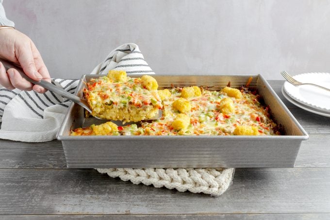 removing a slice of Tater Tot Casserole from a pan