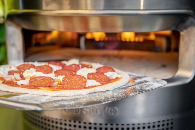 putting in a pepperoni and cheese pizza into a solo pizza oven