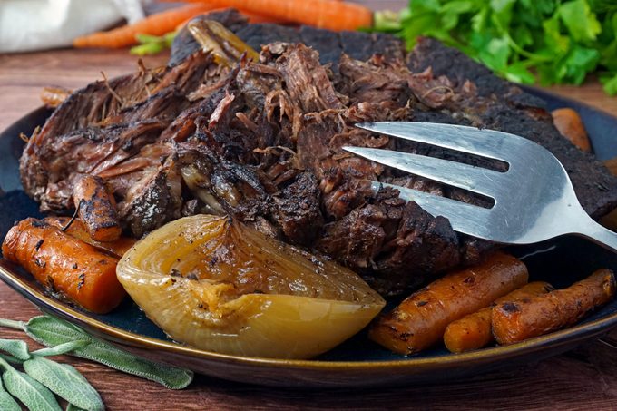a plate with pot roast with carrots and onions