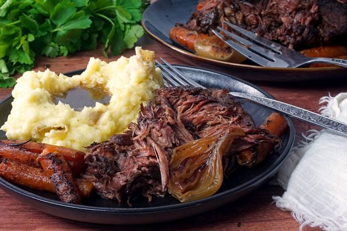 a plate with pot roast with mashed potatoes