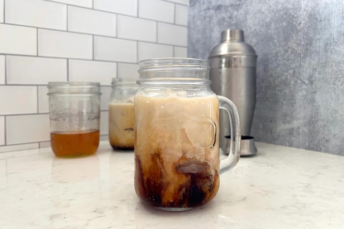 clear mason jar mug with milk mixing into coffee