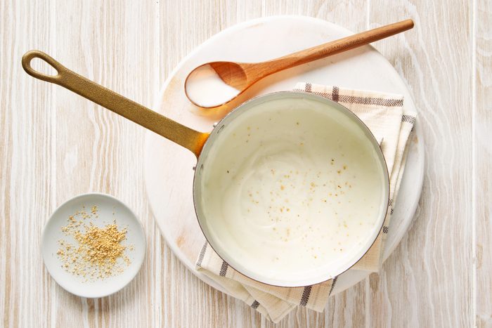 top view of white sauce in a pan with a wooden spoon to the side