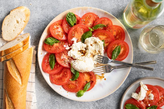 Top view of Burrata Caprese on a plate with a baguette to the side