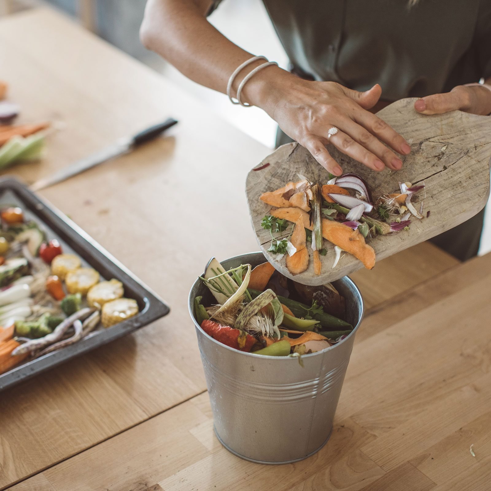 Making Compost From Vegetable Leftovers and food scraps in a bright kitchen and on a wooden countertop