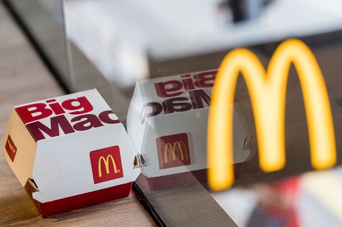 Mcdonalds Big Mac Box Seen on a table inside restaurant with golden arch logo seen through the window