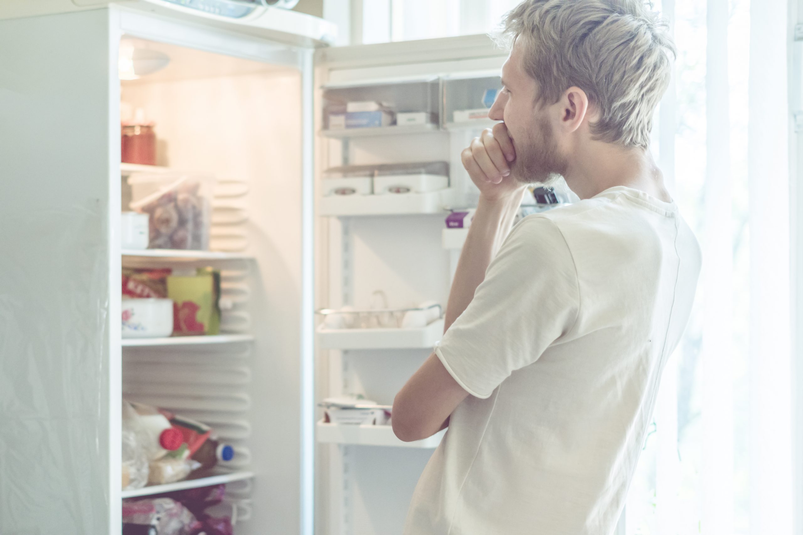 young man searching for food in the fridge at home