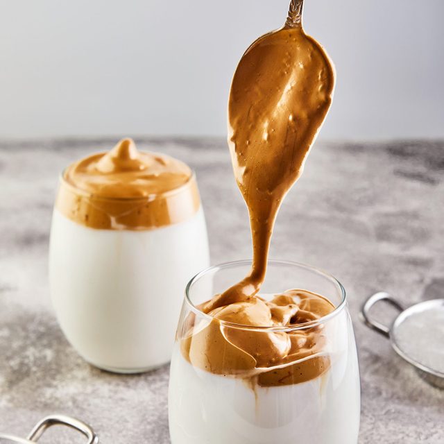 Iced Dalgona Coffee, a cool trendy fluffy whipped creamy coffee. Latte espresso with coffee foam in tall glass and milk