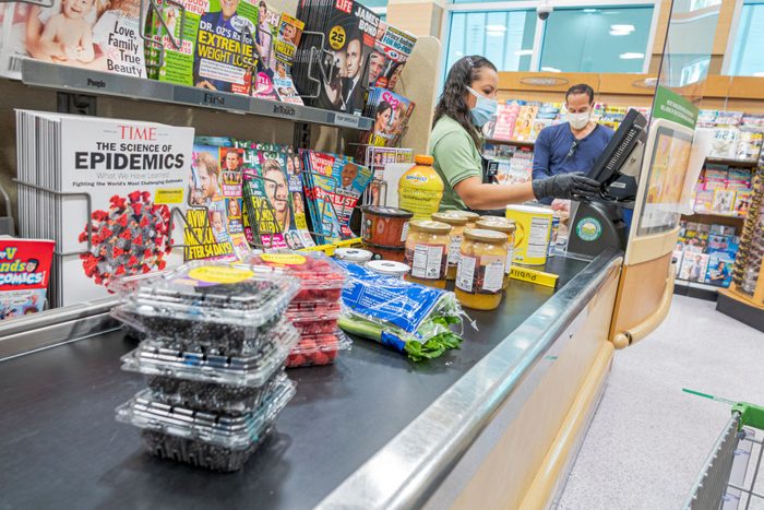 Florida, Miami Beach, Publix grocery store cashier and customer wearing face masks and gloves, the new normal