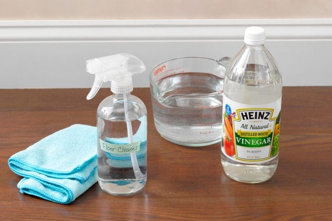 cleaning supplies for homemade laminate floor cleaner arrange on a laminate floor near the wall