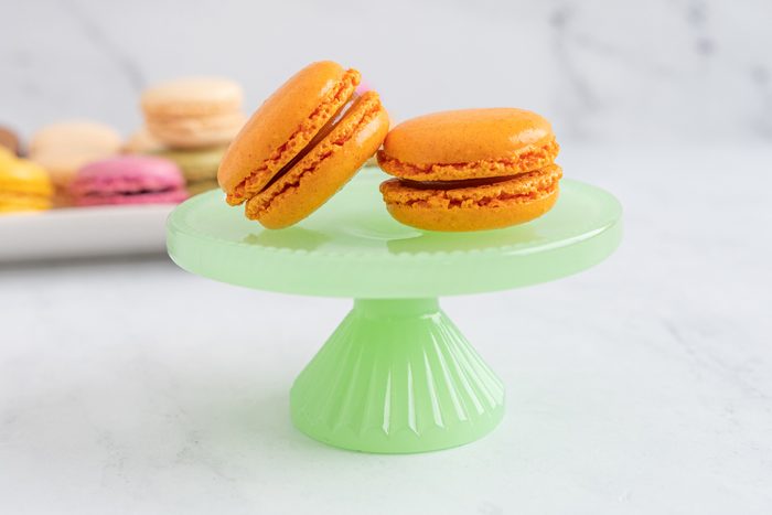 Apricot macaroon on a green plate with a stand