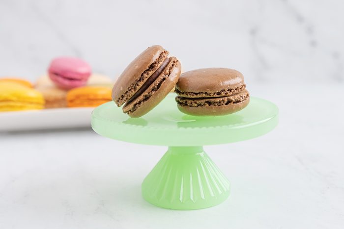 Chocolate macaroon on a green plate with a stand
