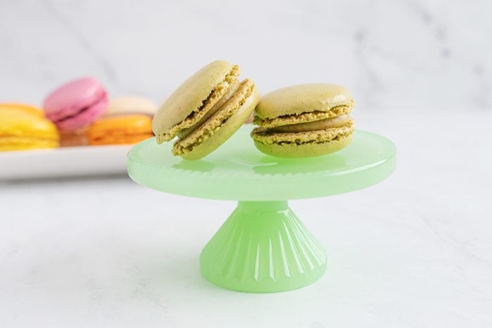  Pistachio macaroon on a green plate with a stand