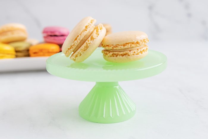 Vanilla macaroon on a green plate with a stand