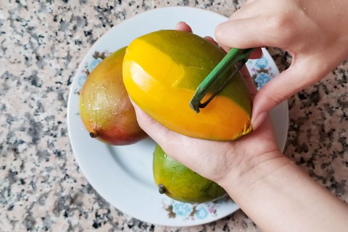 top view of hands pealing a mango