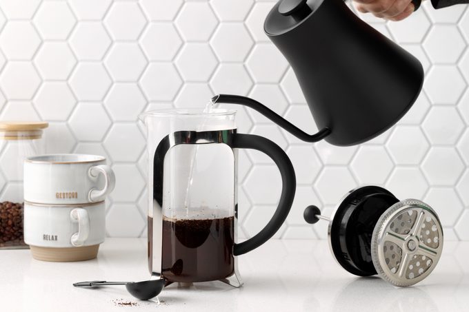 pouring water into a French press from a black goose neck kettle