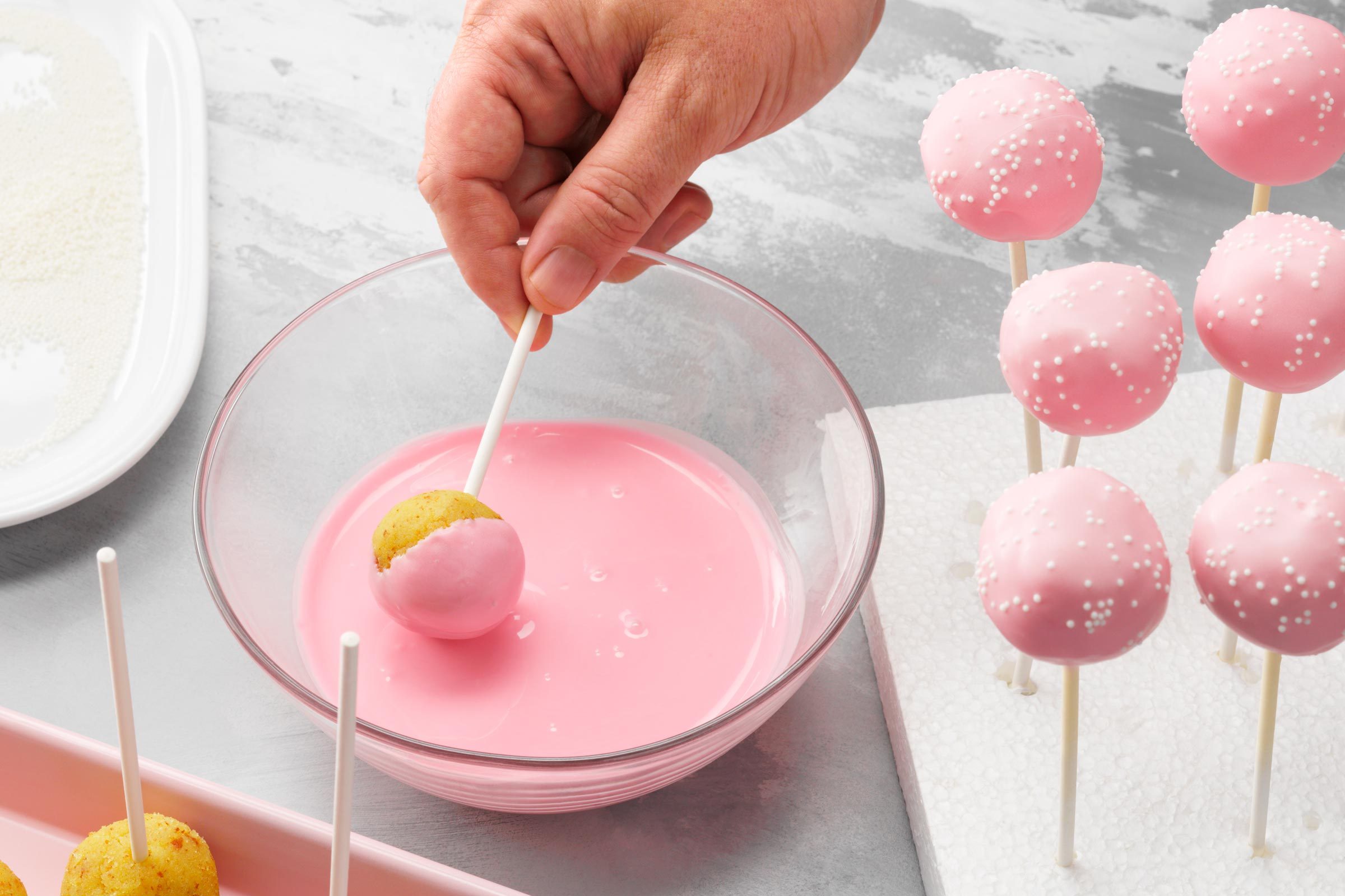 dipping cake pops into pink frosting