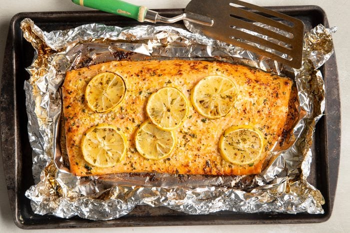 salmon in foil with lemon slices on a baking sheet