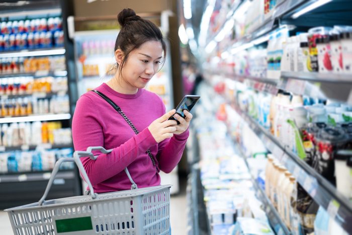 female using smart phone in supermarket