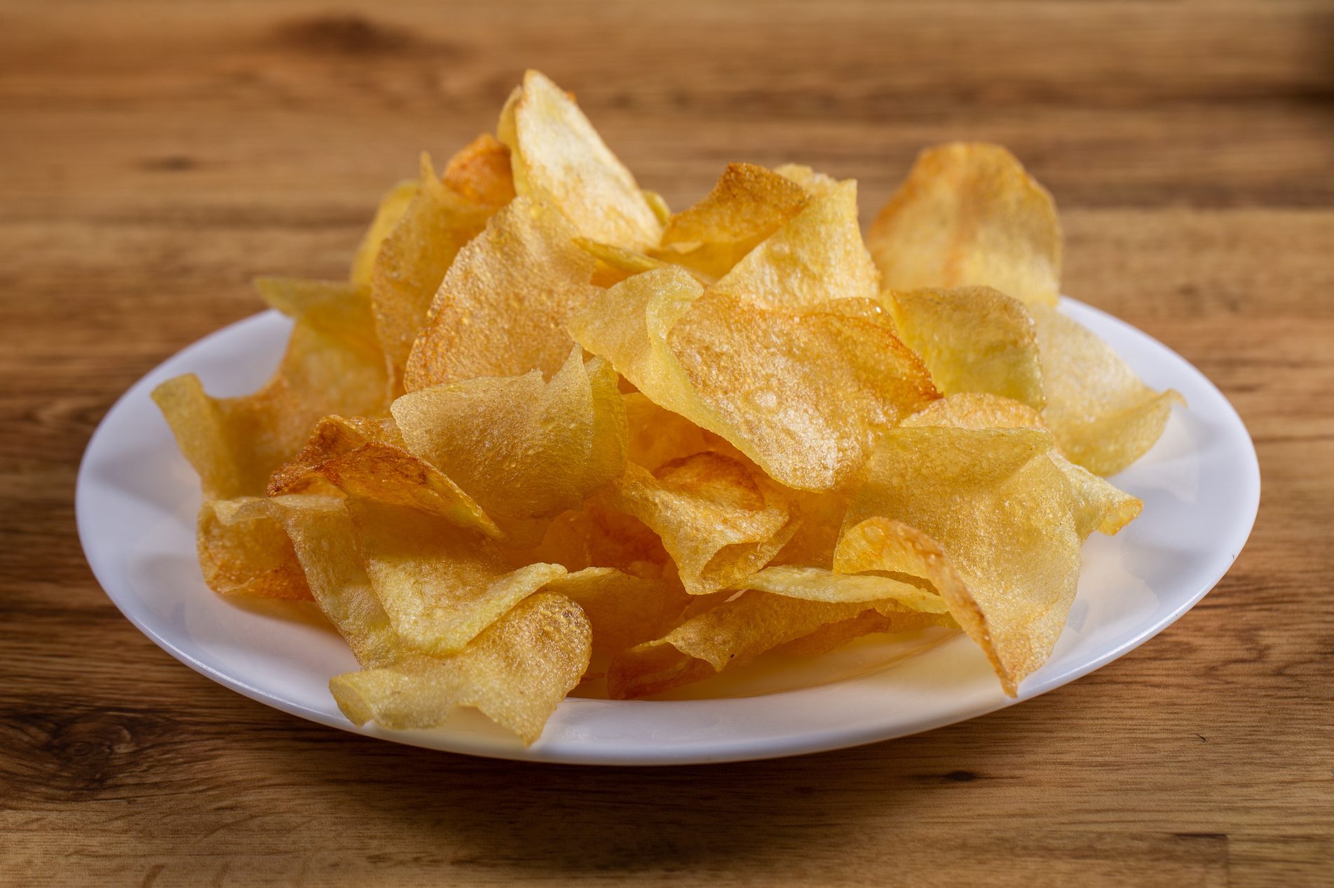 portion of potato chips on wooden background.