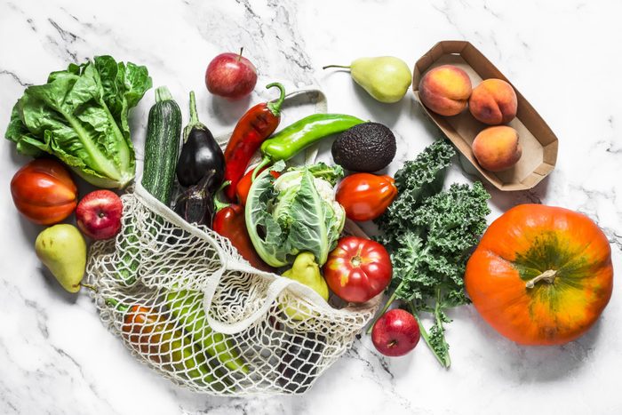 Seasonal vegetables on a marble background - kale cabbage, zucchini, eggplant, pepper, cauliflower, tomatoes, pumpkin and pears, apples, peaches. Top view