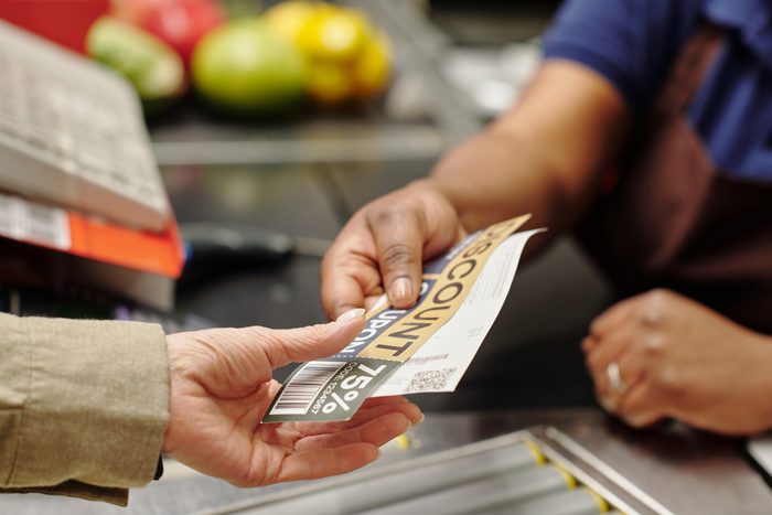 Hand of young female cashier passing discount coupon and receit to customer