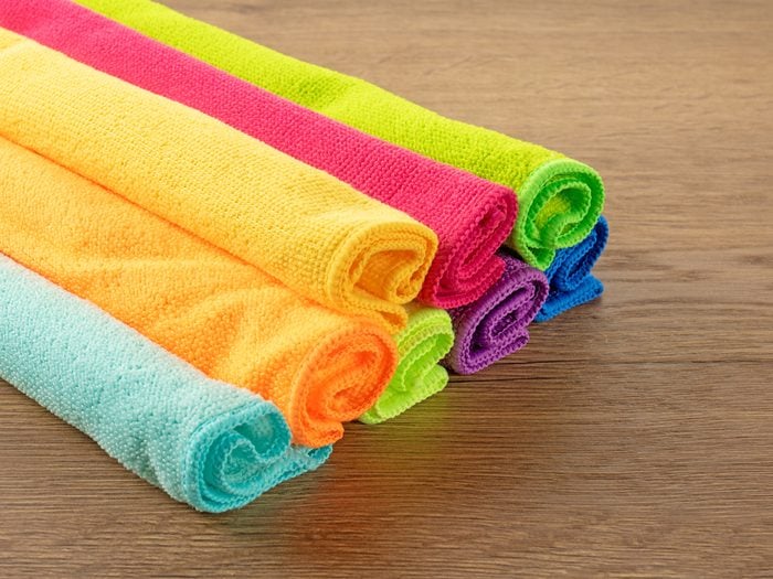 Stack of kitchen microfiber towels in bright colors on a brown wooden table