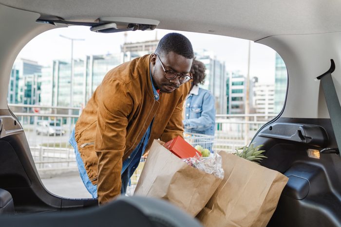 African American couple packing shopping bags from the grocery store in the car trunk