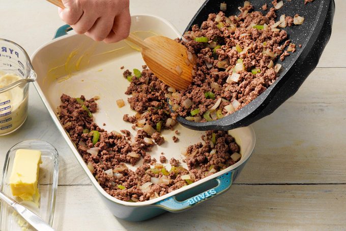 filling a baking dish with cooked beef