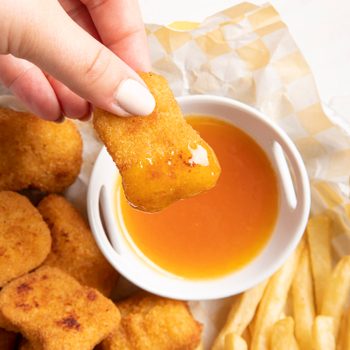 dipping a chicken nugget in Copycat McDonald's Sweet and Sour Sauce