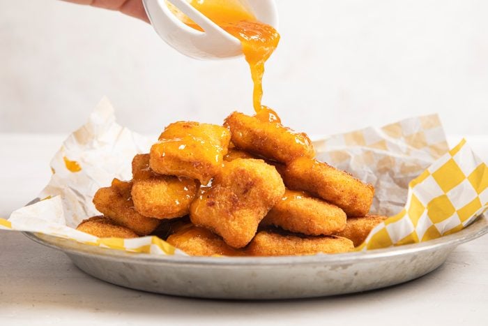 pouring Copycat McDonald's Sweet and Sour Sauce onto chicken nuggets