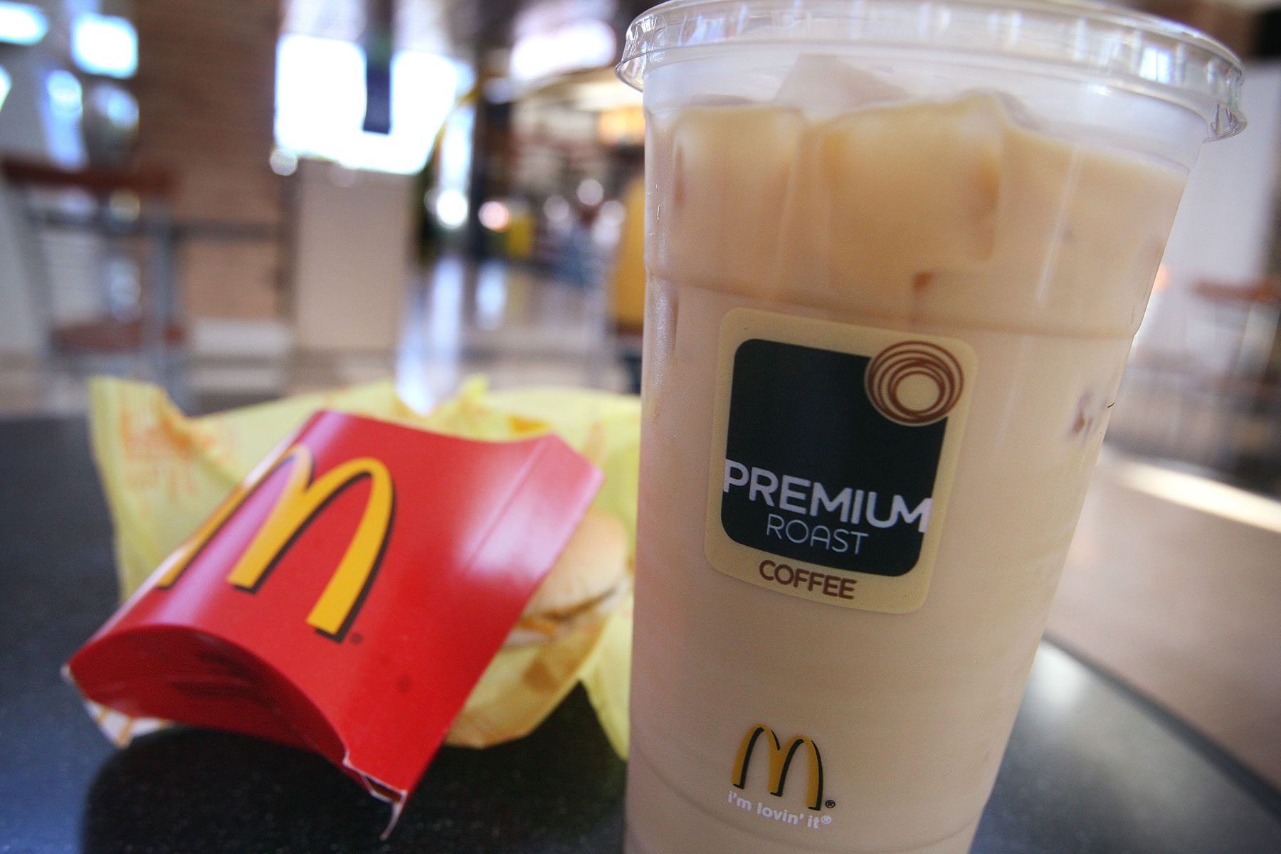 An iced coffee and french fries sit on a table in a McDonald's Restaurant