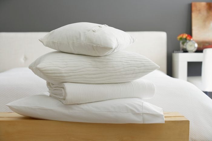 Stack of pillows and a blanket at the foot of a bed