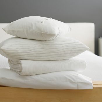 Stack of pillows and a blanket at the foot of a bed