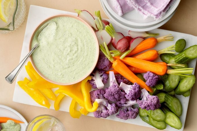 Green Goddess Dip in a bowl on a white platter with an array of colorful veggies