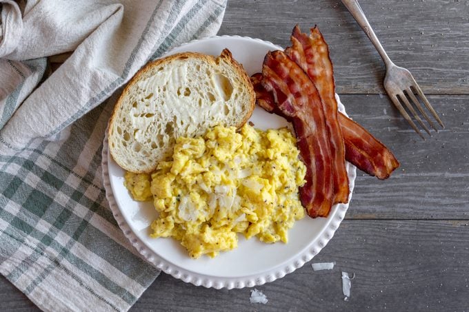 Ina Garten scrambled eggs on a plate with bacon and toast