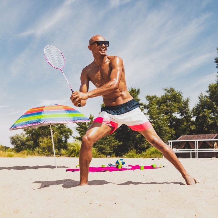 Young Man playing badminton on the beach on a sunny day