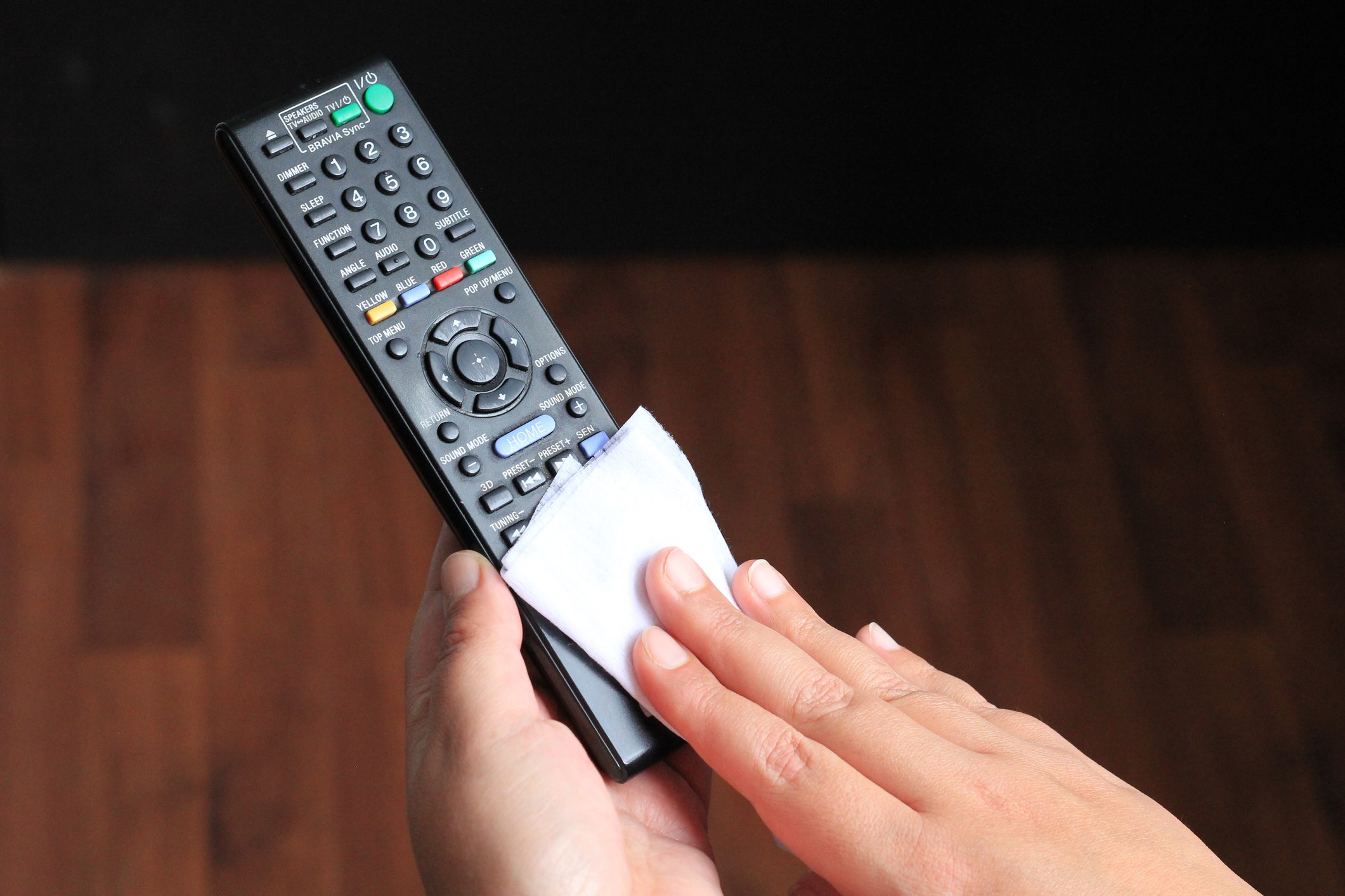 Close up hands showing how to clean the TV remote with a cloth