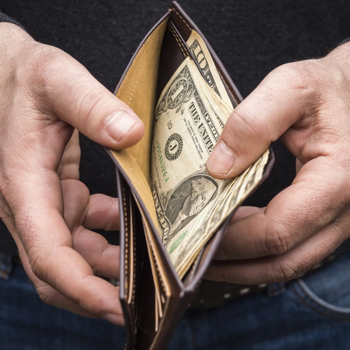 Hands holding a wallet with a small amount of US dollars, close up