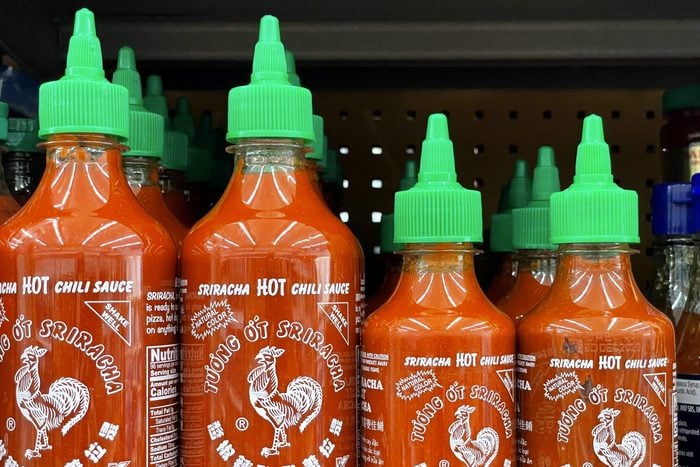 small and large bottles of Sriracha on shelves