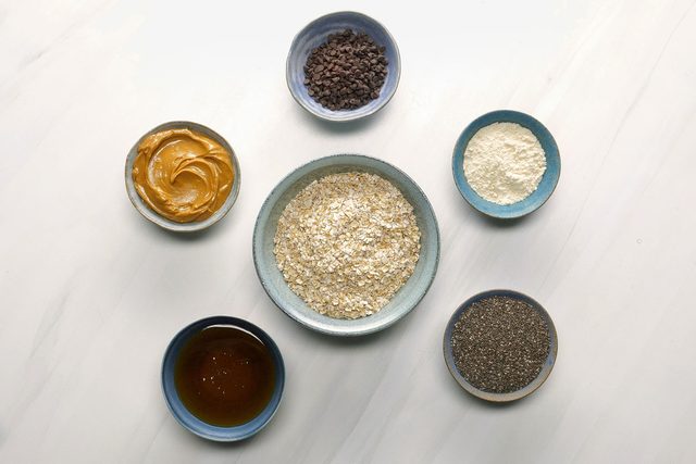 Protein Balls ingredients in small bowls on a light surface