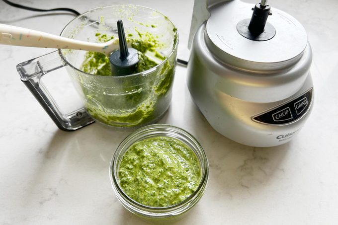 Pesto in a small dish and the food processor in the background