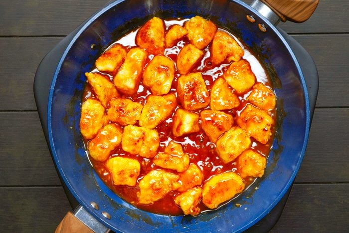 chicken coated in sesame chicken sauce in a blue pan