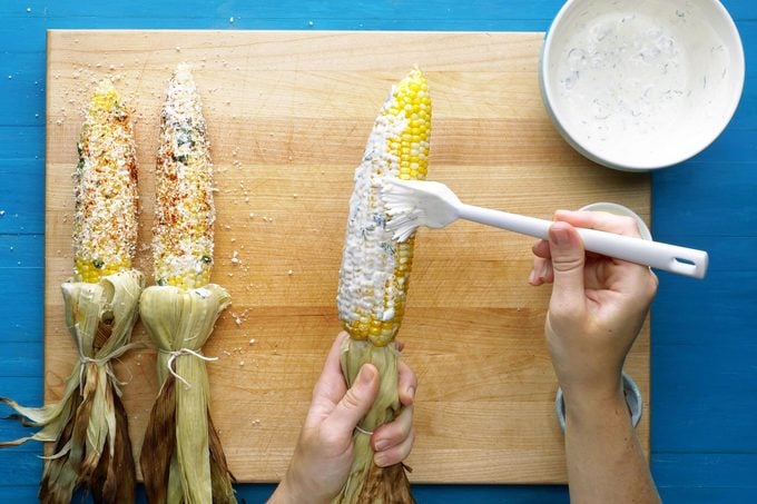 putting mixture onto an ear of corn