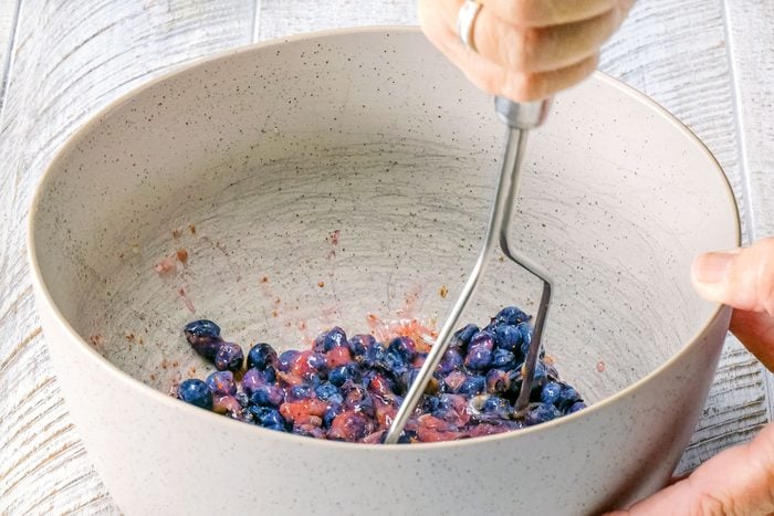 mashing Blueberries in a bowl to make Blueberry Tart Filling