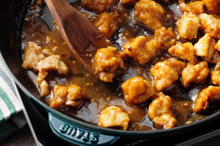 A Pan of General Tso's Chicken with a Wooden Spoon
