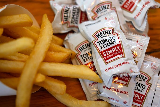 Packets of Heinz ketchup are displayed with Burger King french fries on a wooden table