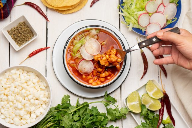 Red pozole with chicken and hominy on white background