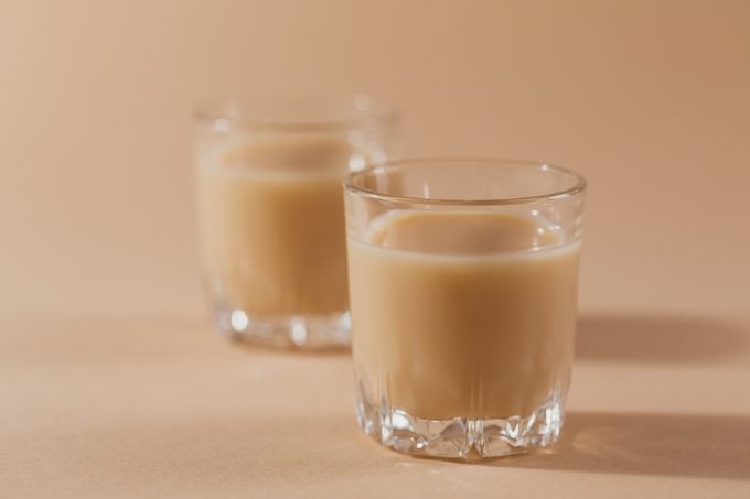Short glasses of Irish cream Liquor or Coffee Liqueur on light beige background