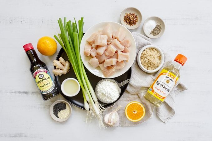 ingredients for Orange Chicken on a white wood table