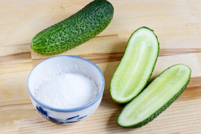 Pickle Salt in a small bowl next to cucumbers on a wooden surface
